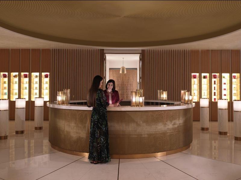 Eleganter Empfangsbereich mit rundem Tresen, warmem Licht und moderner Einrichtung in Beige- und Brauntönen.