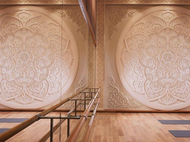Großer Raum mit Holzfußboden, rosa Wänden und zwei symmetrischen, runden, floralen Wandreliefs.