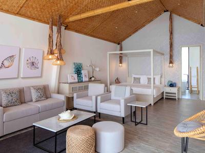 Sala moderna amueblada con muebles claros y acentos de madera en un espacio abierto.