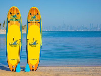 Two yellow lifeguard boards stand on the beach in front of blue sea and clear blue sky.