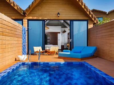 Modern wooden bungalow with private pool, blue loungers, and open glass sliding doors.