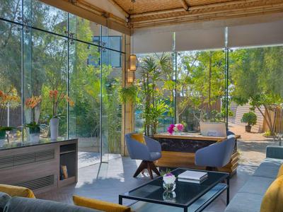Bright, modern living room with glass walls overlooking a garden with trees.