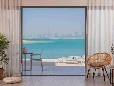 Espacio interior moderno con vista a través de grandes ventanales al mar y ciudad con cielo despejado.