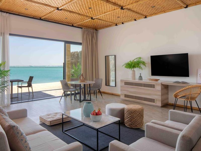 Sala luminosa con muebles modernos y balcón con vista al mar en un hotel.