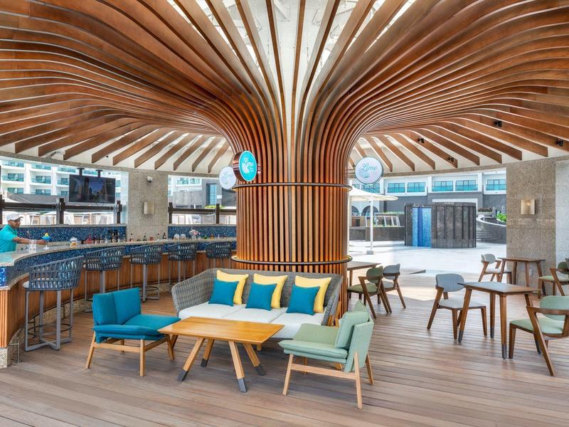 Modernes Café mit breitem Holzsäulendesign, bunten Sitzmöbeln und großen Fenstern.