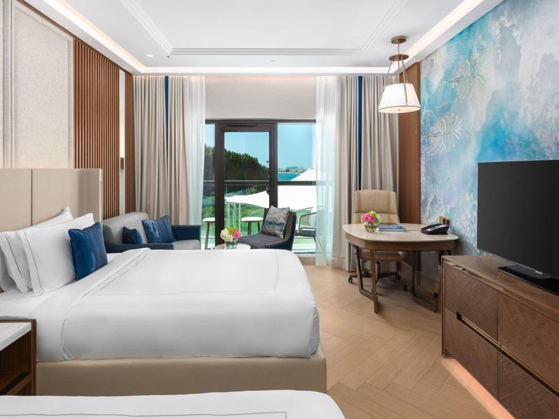 Modernes Hotelzimmer mit zwei Betten, großem Fenster, Schreibtisch und farbiger Wandgestaltung.