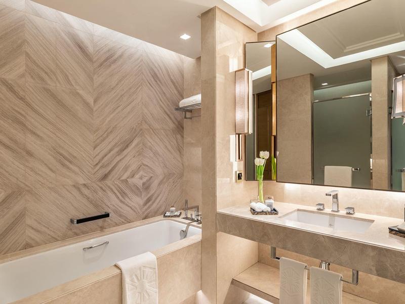 Moderner, hell gestalteter Badezimmerbereich mit Badewanne, Waschbecken, großem Spiegel und warmem Licht.