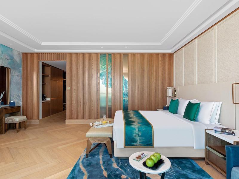 Helles Schlafzimmer mit Holzvertäfelung, Doppelbett, blauer Deko und modernem Teppich.