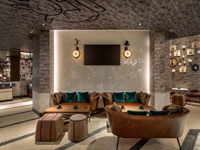 Modern eingerichtetes Wohnzimmer mit braunen Ledersofas, Teppichboden und Wandbeleuchtung.