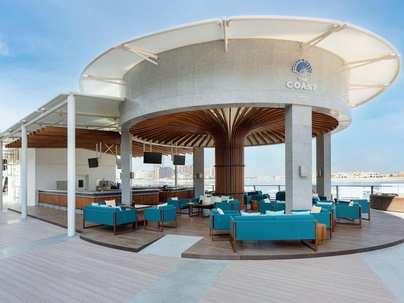 Moderner Außenloungebereich mit blauen Sofas und runder weißer Überdachung auf Holzterrasse.