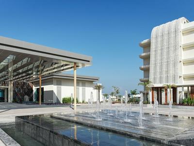 Moderner Hotelkomplex mit Brunnen und Pavillons unter klarem Himmel.