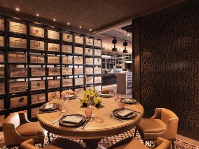 Gemütlicher Essbereich in einem Restaurant mit rundem Tisch und Wandregal für Weinflaschen.