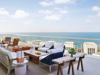 Moderne Terrasse mit bequemen Sitzgelegenheiten und Meerblick bei klarem Himmel.