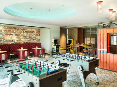 Spielraum mit zwei Kickertischen, Sitzgelegenheiten und moderner Beleuchtung.