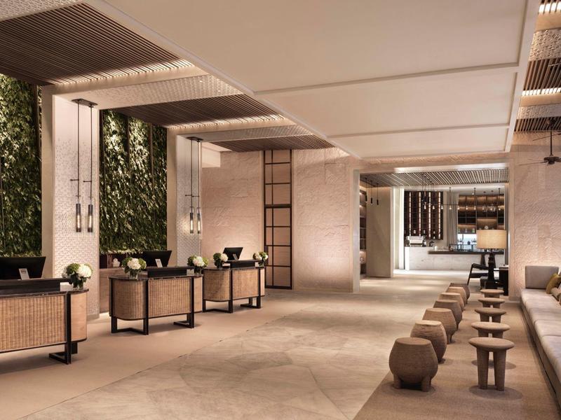 Moderner Empfangsbereich mit hellem Boden, begrünter Wand und minimalistischen Sitzmöbeln.