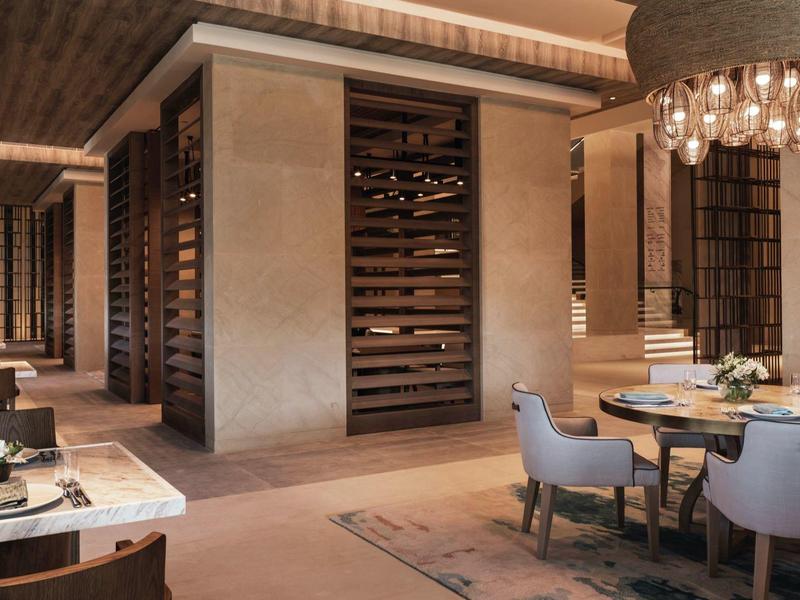 Moderner, gemütlicher Essbereich mit Holzböden, gedeckten Tönen, runden Stühlen und Weinregalen.