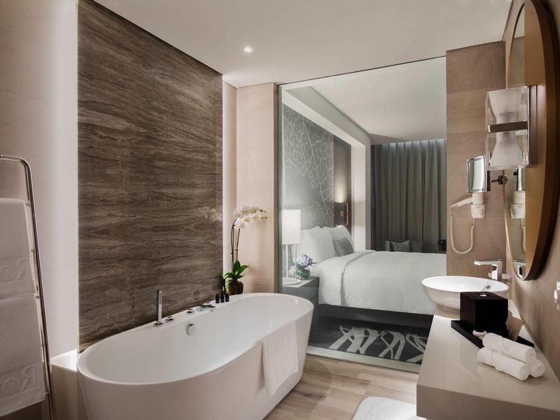 Modern bathroom with freestanding bathtub and view into bedroom.