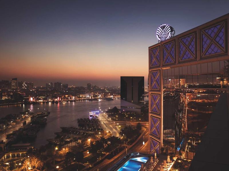 View of a lit river and modern hotel architecture at dusk.