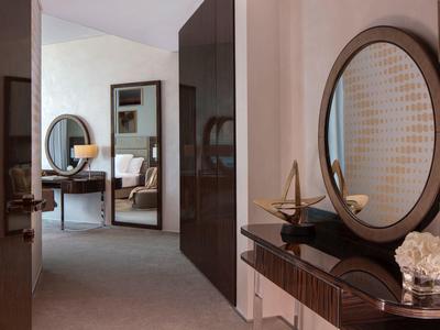 Moderner Flur mit rundem Spiegel, Holzkommode, Dekoobjekten und Blick ins Wohnzimmer mit Stuhl.