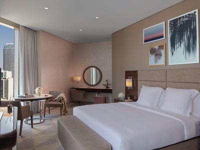 Modernes Hotelzimmer mit großem Bett, Stuhl, Schreibtisch und drei stilvollen Wandbildern.