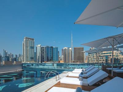 Luksusowy basen na dachu z leżakami i widokiem na miasto.