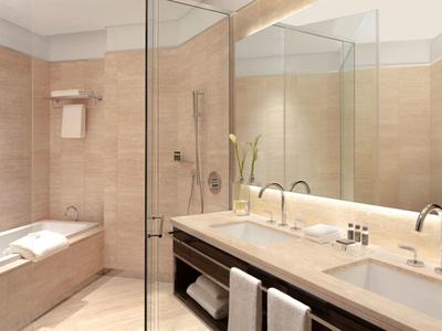 Modernes Badezimmer mit beigem Fliesen, Doppelwaschbecken und Glasdusche, Badewanne in Ecke.