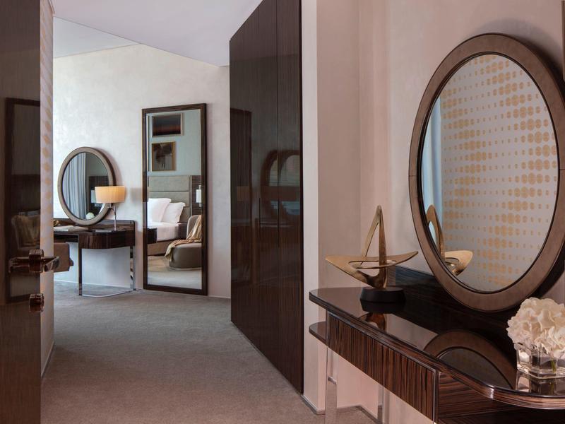 Moderner Flur mit rundem Spiegel, Holzkommode, Dekoobjekten und Blick ins Wohnzimmer mit Stuhl.