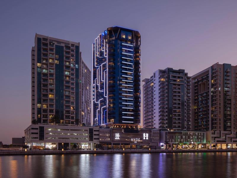 Hochhäuser mit Beleuchtung am Wasser bei Dämmerung und violettem Himmel.