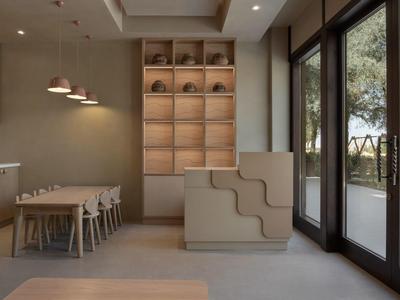 Modern dining area with wooden tables, chairs, and large windows overlooking trees.