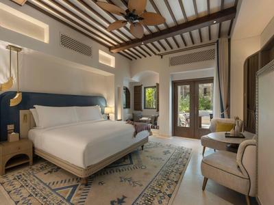 Stylish bedroom with large bed, rug, ceiling fan, and access to balcony.