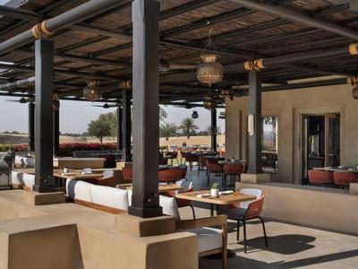 Open outdoor space with wooden roof, modern furnishings, and outdoor seating arrangements.