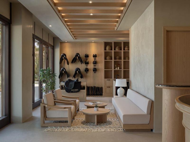 Modern hotel lounge area with sofas, chairs, and wall shelves.