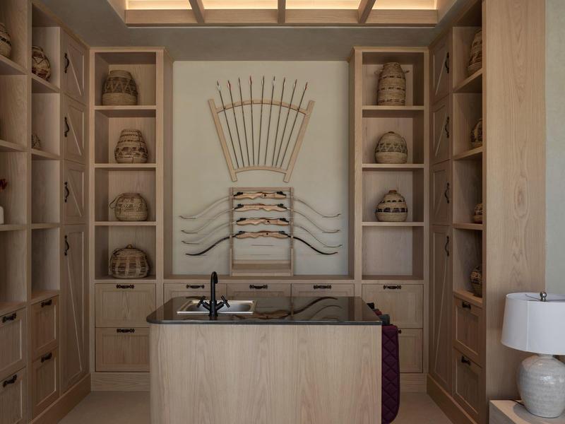 Modern beauty room with sink island and decorative shelves in warm wood tones