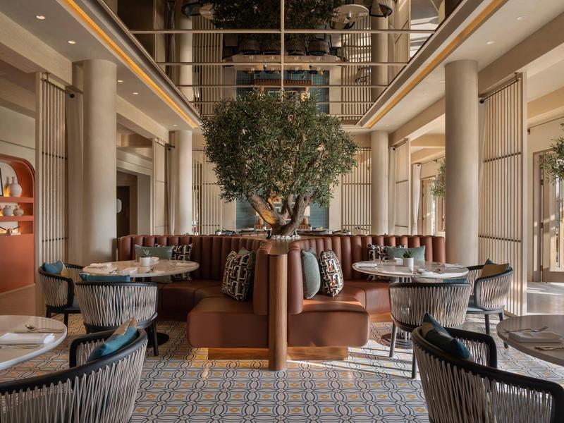 Elegant hotel restaurant with modern seating and green plant decor.