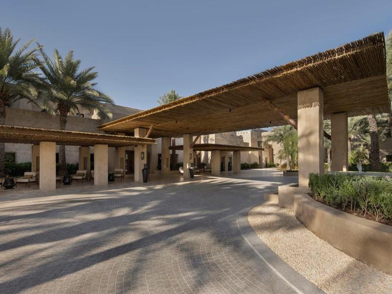 Hotel entrance area with covered walkway and palm trees in the background.