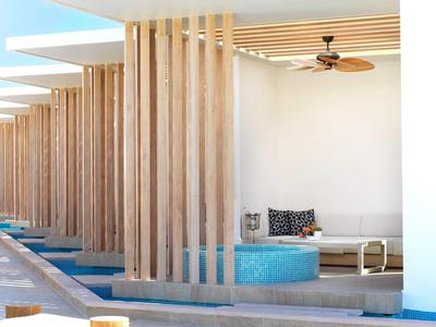 Moderner Außenbereich mit Holzbalken, blauem Pool, weißem Sofa und Deckenventilator.