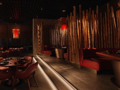 Elegancka restauracja z przyciemnionym oświetleniem i dekoracyjnymi elementami bambusowymi.