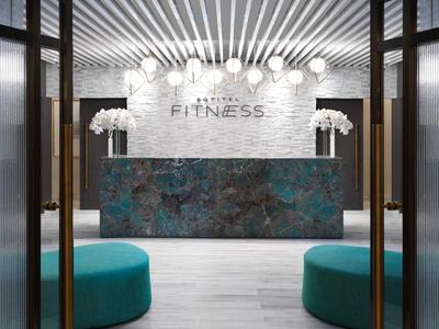 Nowoczesna strefa fitness z marmurową recepcją i turkusowymi miejscami do siedzenia.