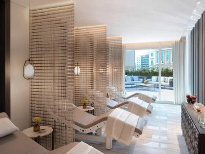 Heller Spa-Raum mit Liegen, Holztrennwänden und Blick auf die Fensterfront zum Außenbereich.