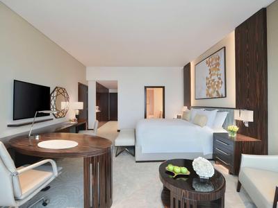 Modernes Hotelzimmer mit Doppelbett, Schreibtisch, Fernseher und gemütlicher Sitzecke.