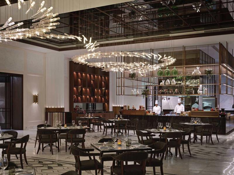 Moderner Restaurantraum mit eleganter Beleuchtung, Holztischen und Stühlen, hellem Marmorboden.