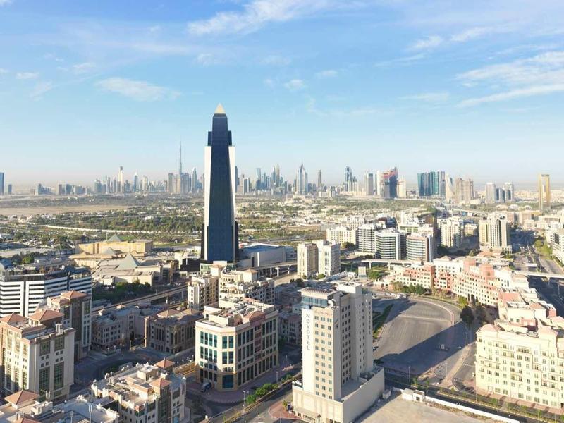 Stadtpanorama mit vielen Gebäuden, hohen Türmen und weiter Wüstenlandschaft im Hintergrund.