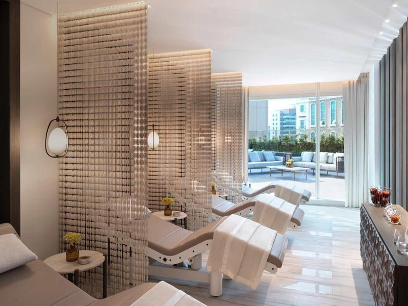 Heller Spa-Raum mit Liegen, Holztrennwänden und Blick auf die Fensterfront zum Außenbereich.