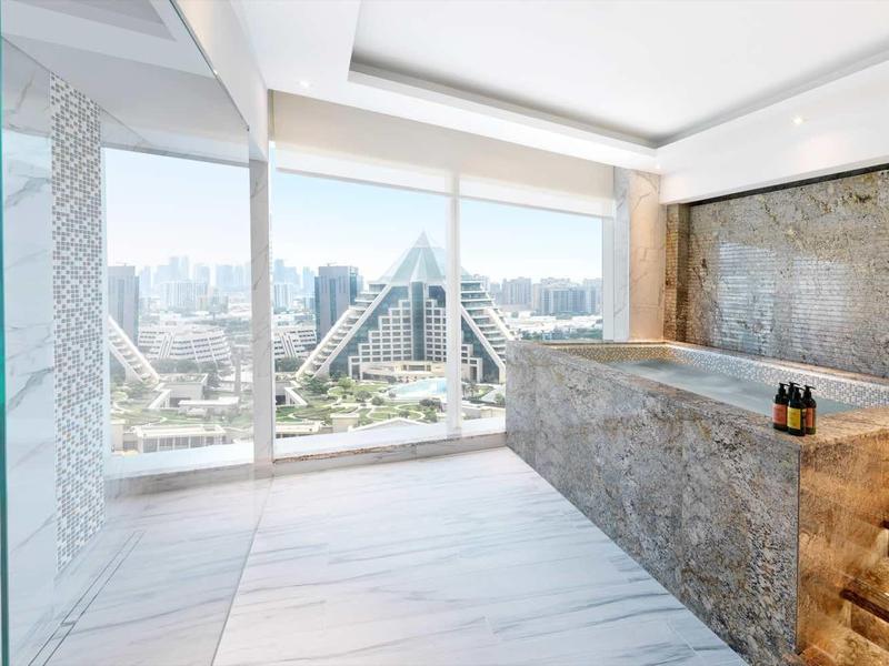 Moderner, heller Wellnessraum mit großer Glasdusche, Steintheken und Panoramafenstern in hellem Holzdesign.