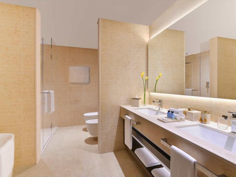 Helles Bad mit beige Fliesen, Doppelwaschbecken, großer Spiegel und moderner Dusche.