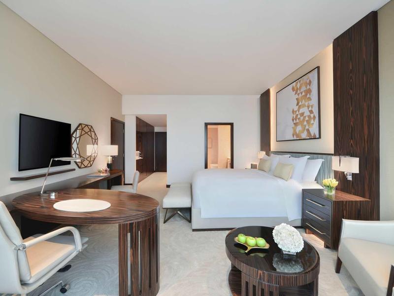 Modernes Hotelzimmer mit Doppelbett, Schreibtisch, Fernseher und gemütlicher Sitzecke.