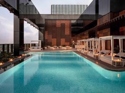 Moderner Außenpool in Luxus-Resort mit entspannenden weißen Liegen und Glasgeländer bei Dämmerung.