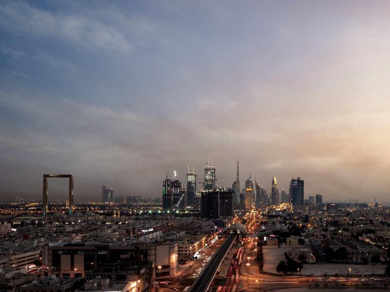 View of a city with skyscrapers at dusk under a cloudy sky.