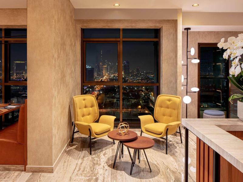 Cozy seating area with yellow armchairs, side tables, and a night city view.