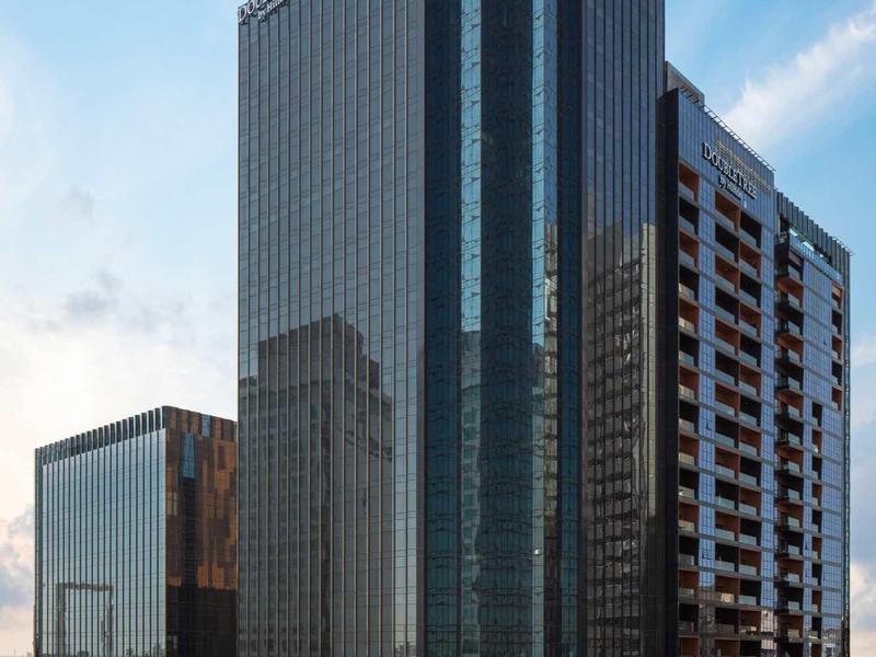 Modern glass-covered skyscraper in a city under clear sky.